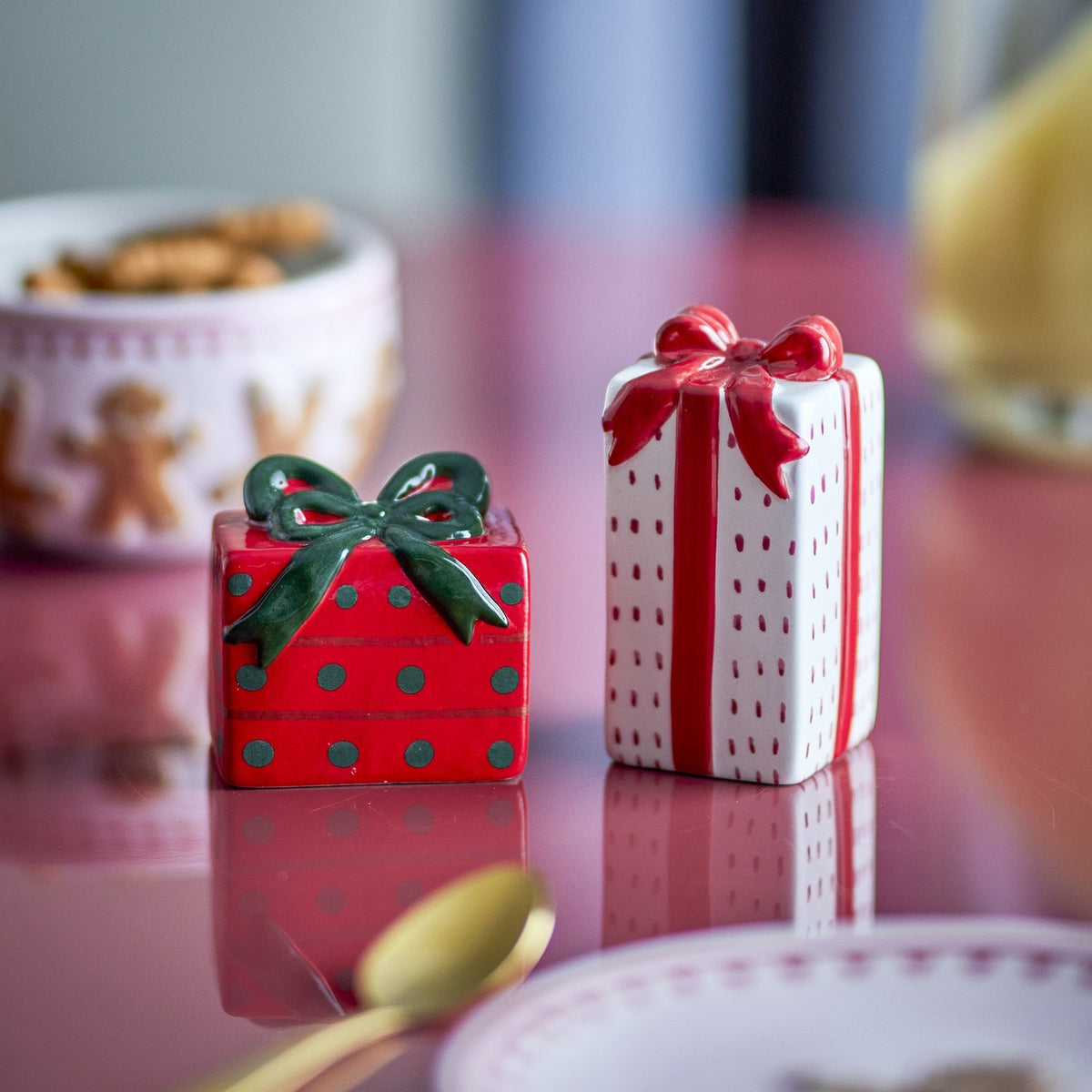 Marnia ceramic salt and pepper shakers shaped as wrapped gift boxes, one short red box with green polka dots and bow, the other tall white box with red stripes and bow.
