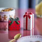 Marnia ceramic salt and pepper shakers shaped as wrapped gift boxes, one short red box with green polka dots and bow, the other tall white box with red stripes and bow.