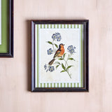 Renji Wooden Framed Print 35.5cm in multicoloured, depicting a songbird on a flowering branch with green striped border, in a firwood frame with glass front, hung on a light wall.