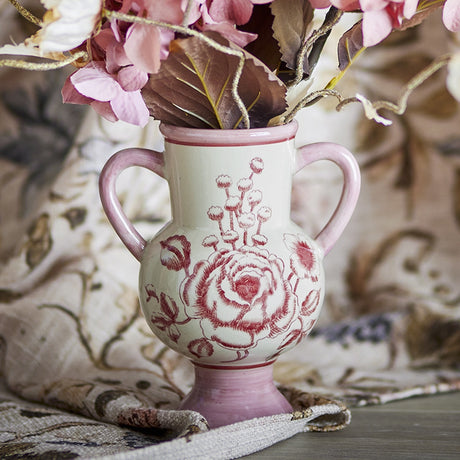 Alea Floral Stoneware Vase 21cm in pink, round belly with two loop handles and pedestal foot, hand-painted rose and floral design, shown with dried flowers.