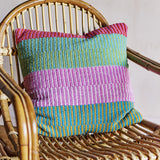 Isnel Pink Striped Cushion in multi colourways, a square woven cushion with ribbed horizontal stripes, shown resting on a rattan chair.