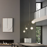 Lumorne 4 Light Glass Globe Chandelier in polished brass, with opal glass globes at staggered heights, shown above a dining table in a modern living space.