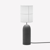Rania table lamp with a rounded anthracite concrete base and a cylindrical white cream fabric shade featuring stitched grid lines, shown on a plain white background.
