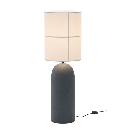 Rania Floor Lamp with a tall, rounded anthracite concrete base and a cylindrical white cream fabric shade with fine seam lines, shown lit against a plain white background.