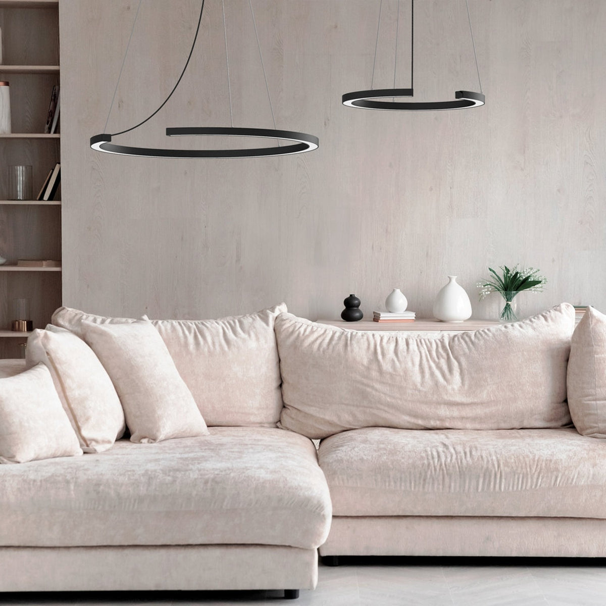Roberta LED Ring Pendant Light in matt black aluminium, two open-circle fixtures at different heights above a beige sofa in a living room.