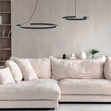 Roberta LED Ring Pendant Light in matt black aluminium, two open-circle fixtures at different heights above a beige sofa in a living room.