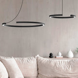 Roberta LED DALI dimmable ring pendant lights in matt black aluminium, shown in two sizes above a beige sofa in a living room setting.