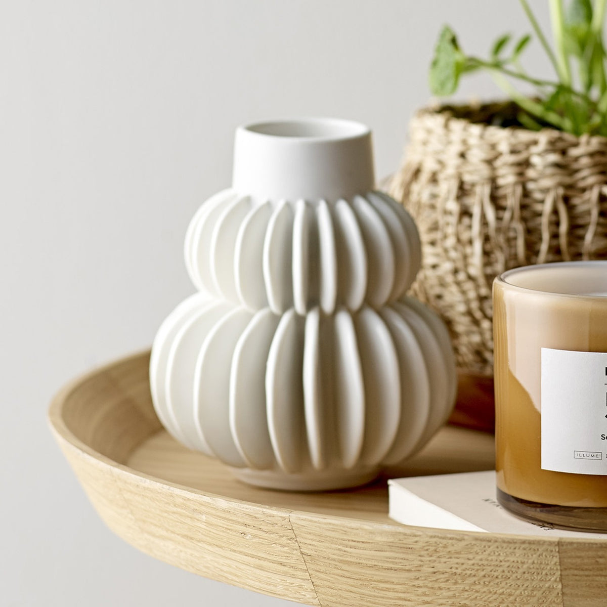 Halfdan Stoneware Vase 14cm in white, with ribbed, two-tiered stacked body and narrow neck, shown on a wooden tray beside a candle and woven plant basket.