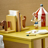 Charlie Dog Bookends Set of 2 in multicoloured MDF, shaped as a dog's head and tail, holding books on a yellow desk beside a wooden toy scene.