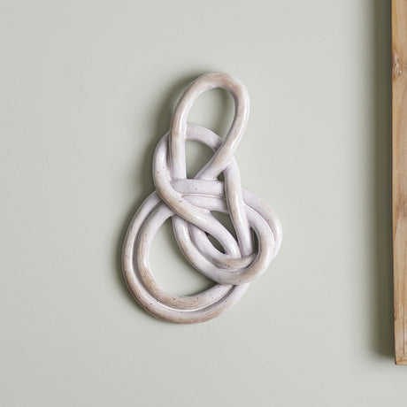 Sifan Resin Wall Decor in beige, a knotted polyresin loop sculpture with a brushed, speckled finish, mounted on a plain light green wall.