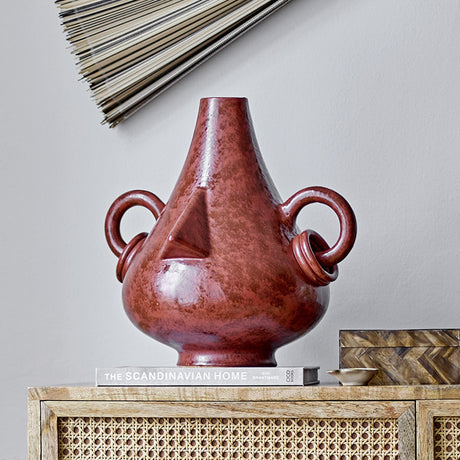 Tarun Stoneware Vase 35.5cm in brown with a teardrop body, sculpted nose, and ring handles with linked hoops, shown on a sideboard in a living room setting.