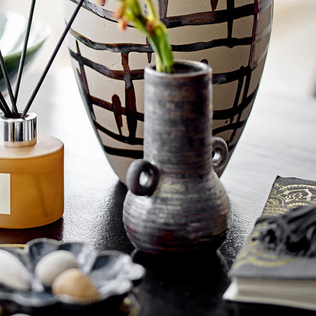 Casaya Stoneware Vase 13.5cm in brown with ringed handles and a textured, ridged body, displayed on a dark table beside a patterned ceramic vase and books.