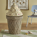 Cillie Seagrass Basket with Lid 72cm in Natural, shaped like an ice cream cone with a woven criss-cross body and a stepped swirl lid dotted with coloured sprinkles, shown in a nursery setting.