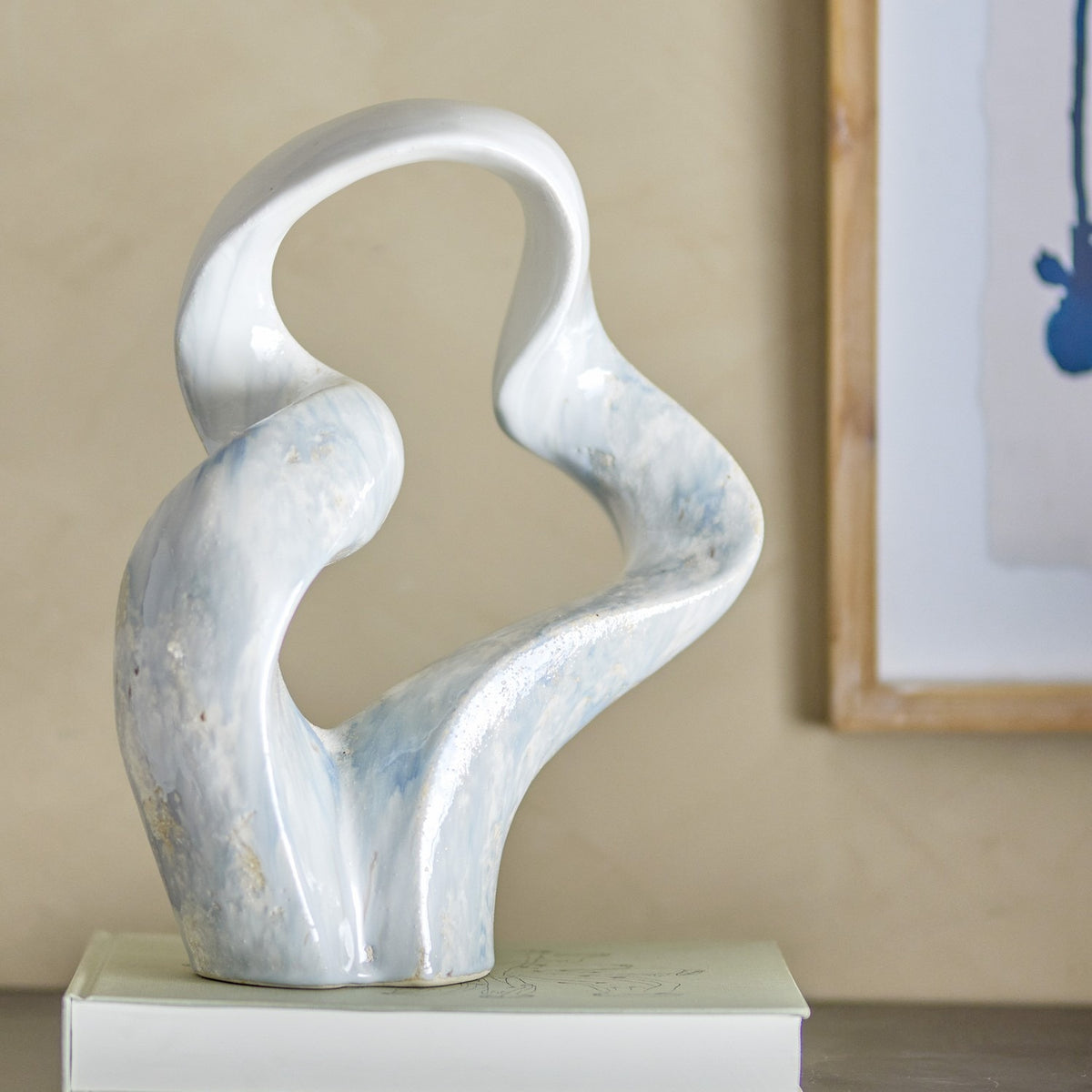 Rouyi Stoneware Ornament in grey, a sculptural ceramic piece with twisting curved arms forming a looped top, glazed in pale and deep grey tones, displayed on a plinth indoors.