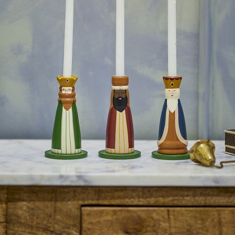 Betiel wooden Christmas candle holders, set of three bearded king figures in green, red and blue robes with crowns, holding white taper candles on a marble surface.
