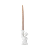Medea resin candle holder in white, shaped as a classical draped female bust holding up a column cradle, with a tall brown taper candle, on a plain white background.