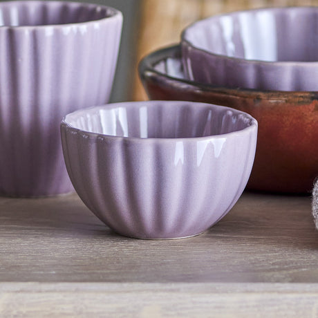 Latina Stoneware Bowl 9cm in pink, small fluted ceramic bowl with vertical ribs and glossy glaze, shown amid matching ribbed cups and bowls on a wooden surface.