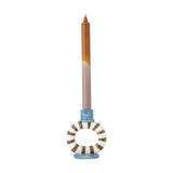 Tacana stoneware candle holder with a brown and white striped open ring, blue-glazed cup and oval foot, holding a tall taper candle on a plain white background.