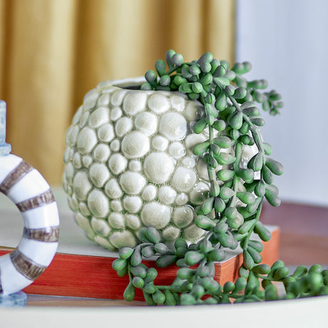 Susannah Crackle Stoneware Plant Pot in green with raised pebble texture and glossy crackled glaze, holding a trailing string-of-pearls plant on a tabletop setting.