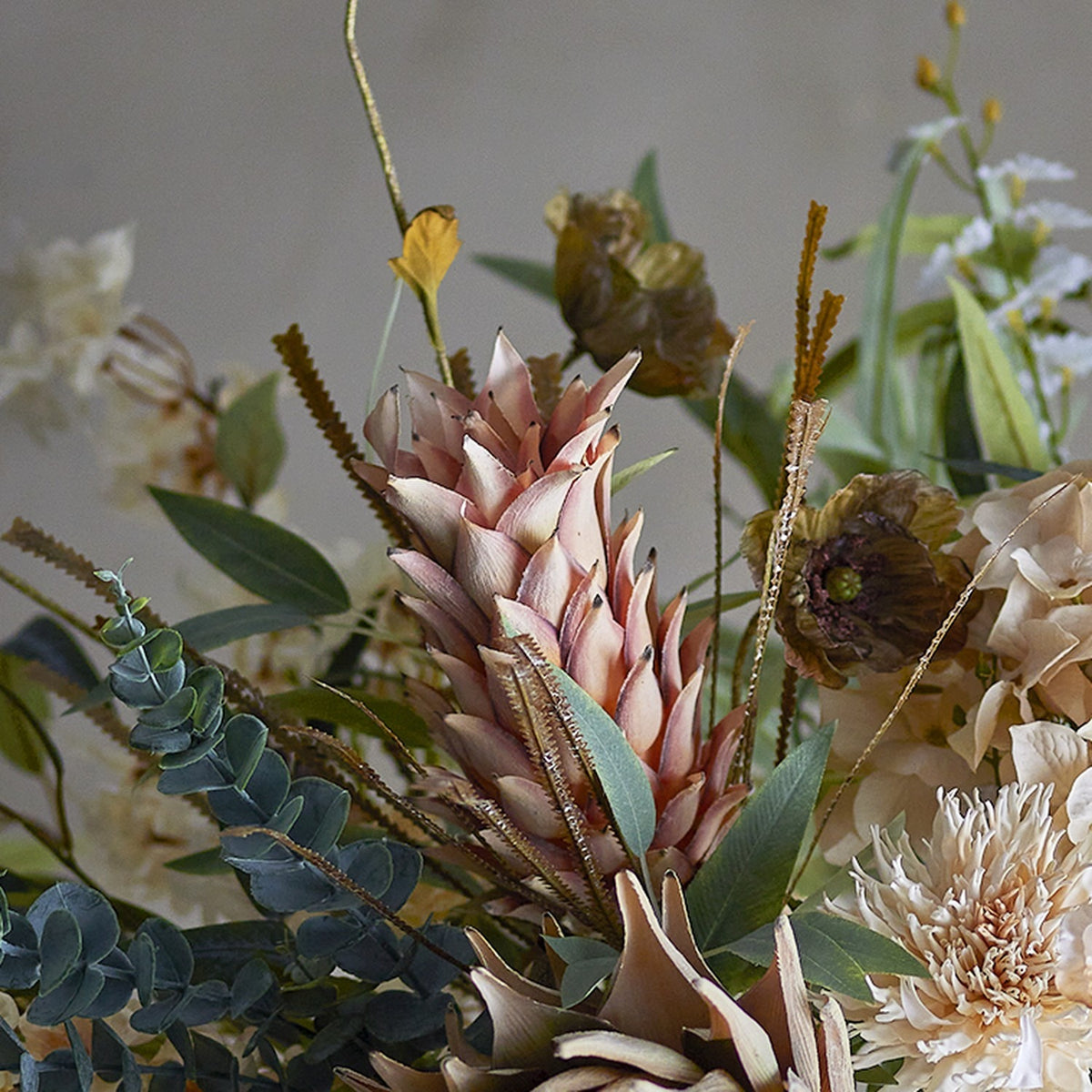 Palmflower Artificial Stem in pink, a cone-shaped faux flowerhead with overlapping petals among fringed leaves, mixed foliage and dried blooms in a styled arrangement.
