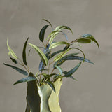 Eucalyptus Artificial Stem 101cm in Green, arranged in a green ceramic vase with narrow curving leaves in varied shades, set against a plain grey background.