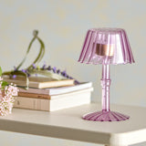 Cisco Glass Tealight Holder 18cm in pink, shaped like a table lamp with a fluted shade and ribbed stem on a scalloped foot, displayed on a shelf beside books and flowers.