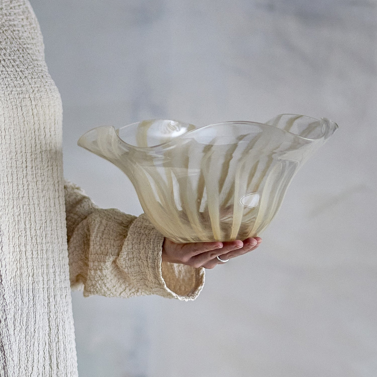 Imri Striped Glass Bowl 32x30cm in Beige with a wavy rim, held in hand against a neutral background to show scale.