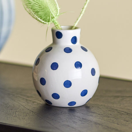 Fian Dotted Ceramic Vase 11cm in White, round globe shape with blue polka dots and narrow neck, holding greenery on a dark wood surface indoors.