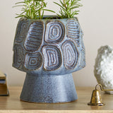Blue Clarke stoneware plant pot, a footed ceramic planter with ringed and ridged textured panels, shown holding a rosemary plant on a wooden surface.