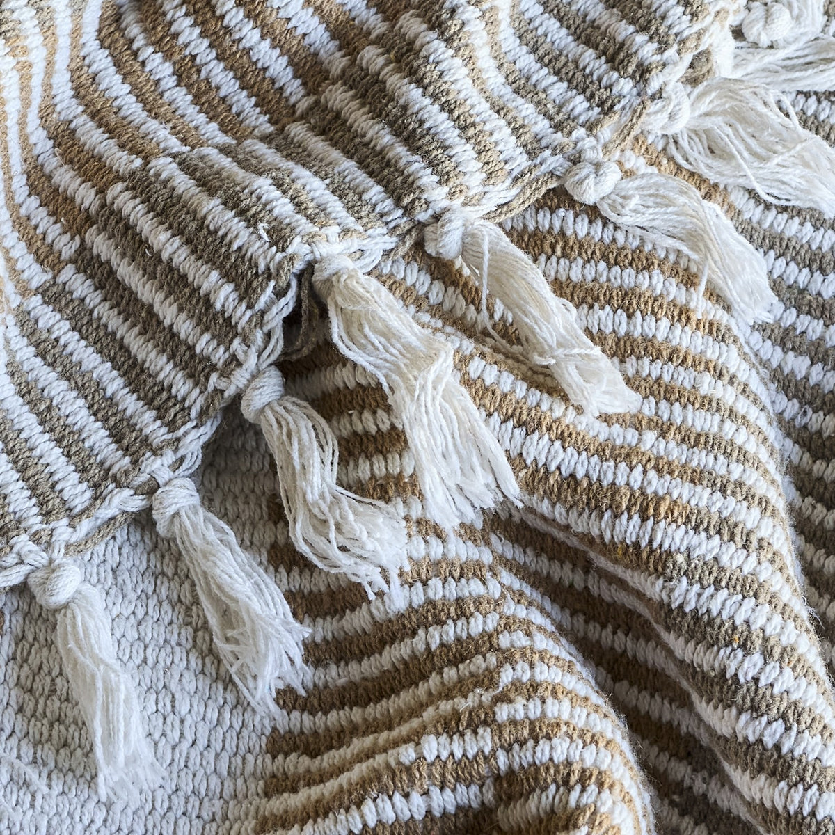 Close-up of the Isnel Brown Striped Cotton Throw showing ribbed woven stripes in brown and white with a knotted fringe edge.