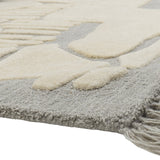 Close-up of the Napoli wool rug in grey, showing raised ivory abstract shapes on a flat woven base with a fringed edge.