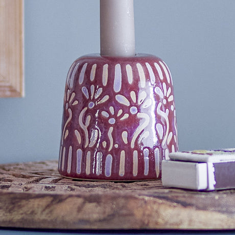 Samsin Stoneware Candle Holder in red, a dome-shaped ceramic base with a pale floral and dash pattern, holding a taper candle on a wooden tray beside a matchbox.