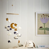 Dolly Star Baby Mobile in white hanging in a nursery, with fabric sheep, moon, stars and clouds on cords beneath a round wooden hoop.