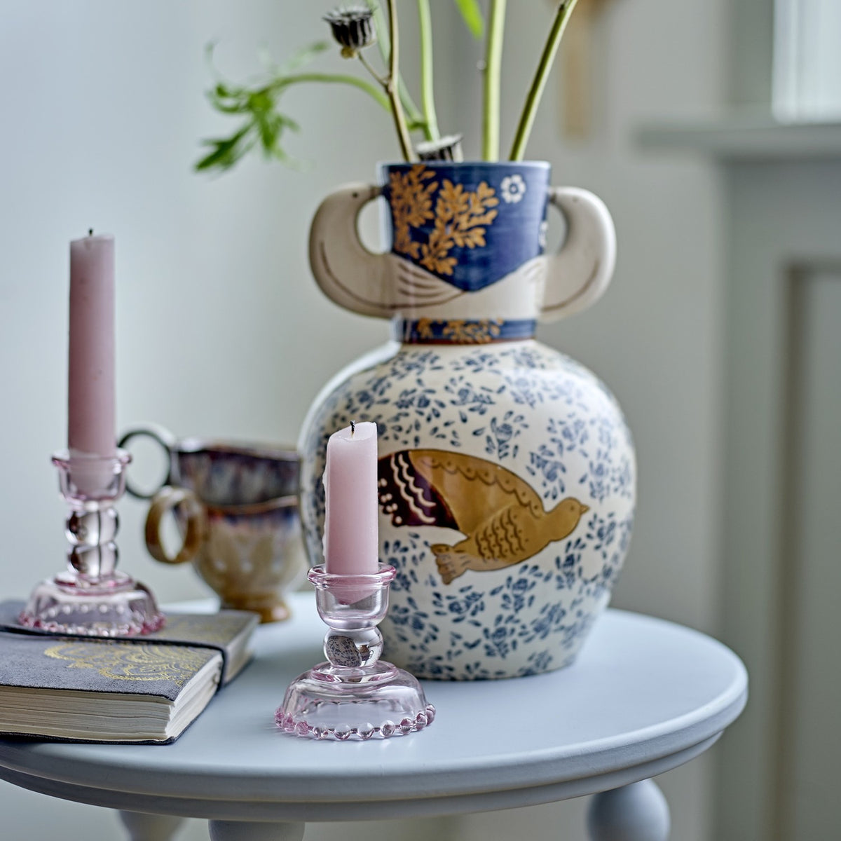 Hezha Floral Stoneware Vase 23.5cm in blue, round body with bird motif and floral pattern, bird-head handles, styled on a side table with candlesticks and a book.