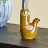 Trudy Bird Stoneware Candle Holder in glossy brown with a pink painted wing and white loop rim, holding a taper candle on a dark wood surface.