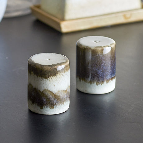 Paula Stoneware Salt & Pepper Shakers Set of 2 in Grey, cylindrical stoneware with reactive glaze showing brown-grey drip patterns, shown on a dark surface.