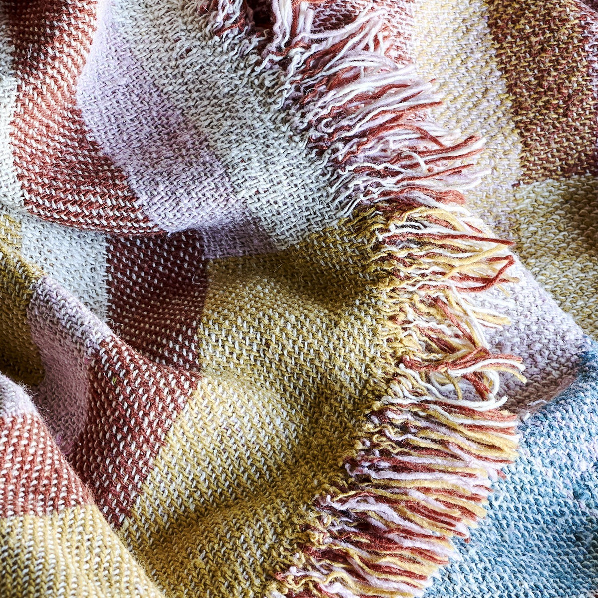 Close-up of the Lane Striped Throw in multicoloured block stripes, showing the woven cotton-blend fabric and long loose fringe edging.