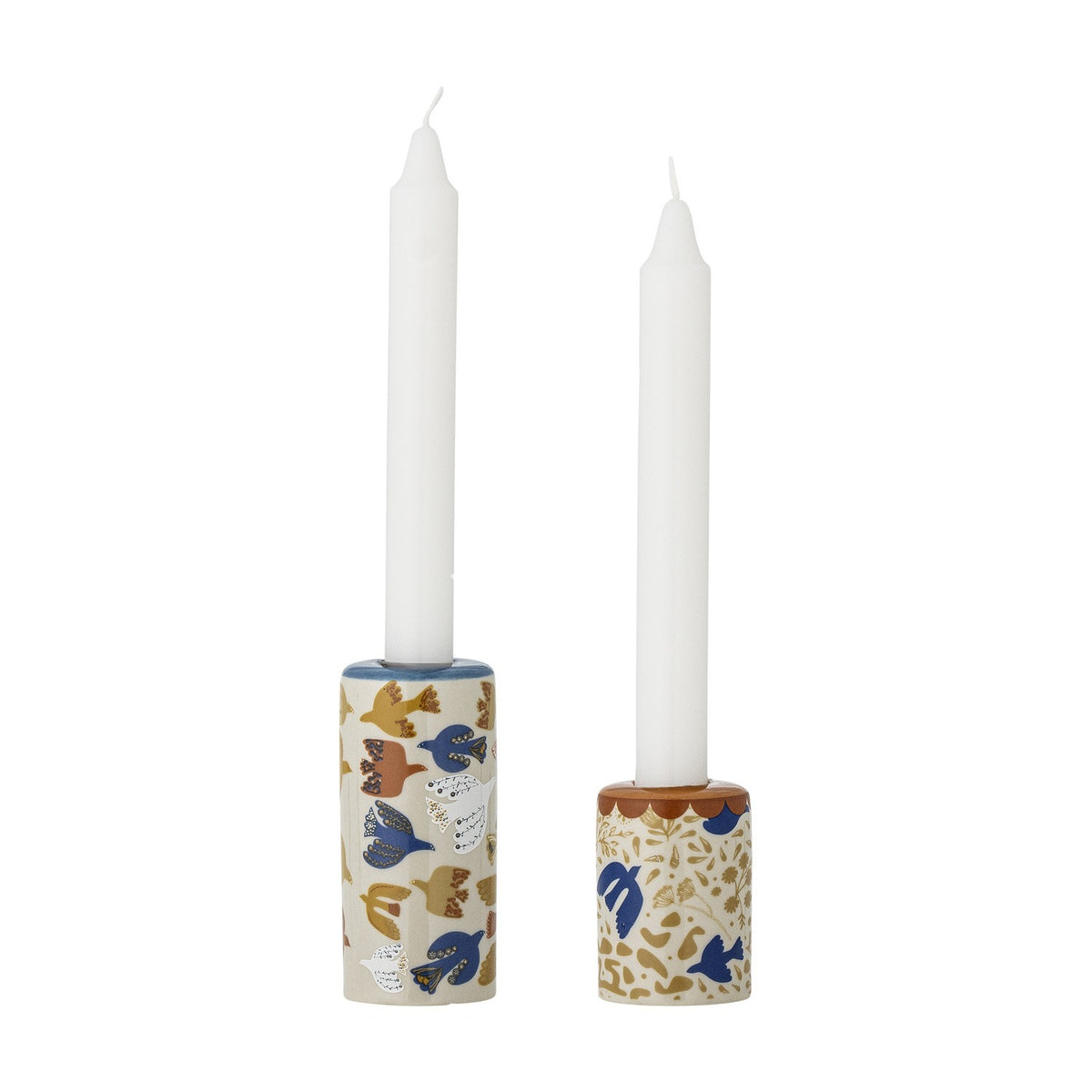 Set of two cylindrical stoneware candle holders in tall and short sizes, each decorated with a multicoloured bird and floral pattern, holding white taper candles on a plain white background.
