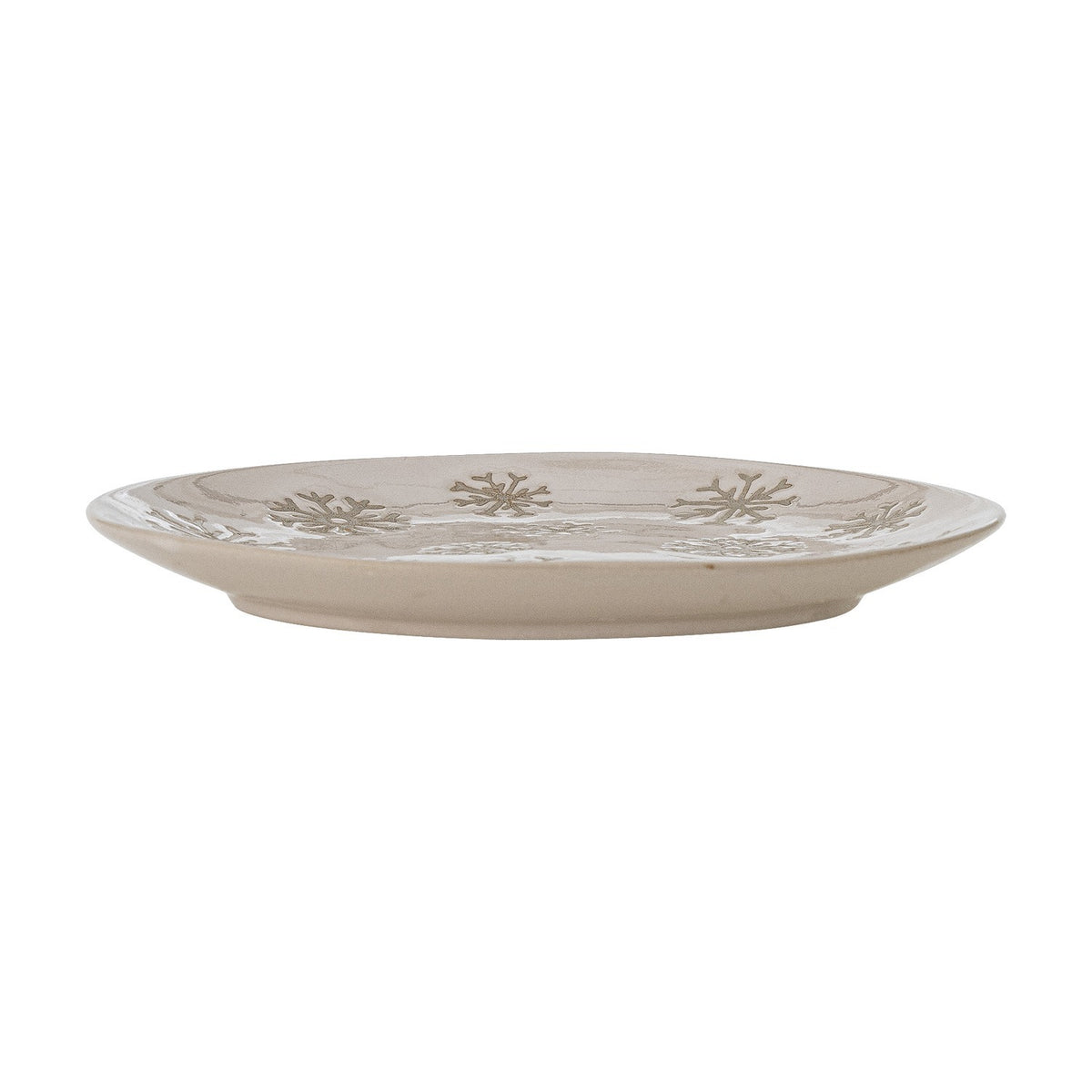 Side profile of a round beige stoneware plate from the Snowie set, showing its low rim and embossed snowflake pattern around the edge, set against a white background.