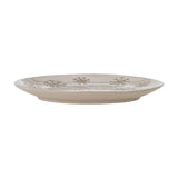Side profile of a round beige stoneware plate from the Snowie set, showing its low rim and embossed snowflake pattern around the edge, set against a white background.