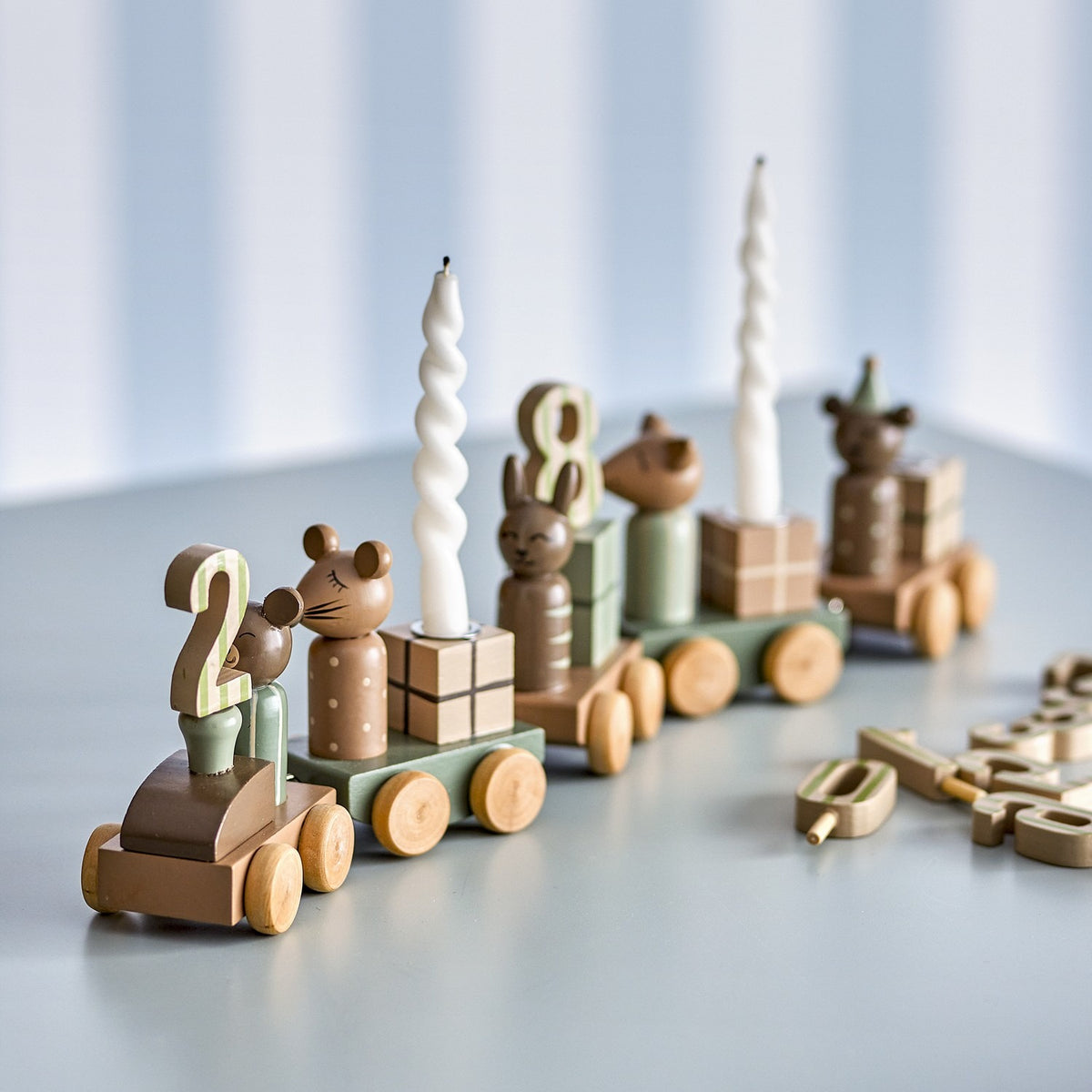 Junaid Dark Brown Birthday Decoration wooden train with mouse, bunny, and bear figures, gift block carriages, number pegs, and candle holders on a light grey surface.