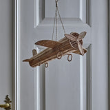 Balazar Rattan Baby Mobile in natural woven rattan, shaped as an aeroplane with wings, tail fin, propeller and wheel-like hoops, hanging by cord against a panelled door.