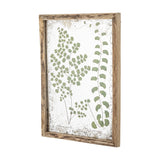 Tipper Wooden Framed Print in Green, showing two botanical fern illustrations on a weathered, speckled background within a rustic wooden frame, shown at an angle against a plain background.