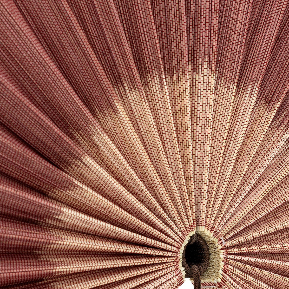 Close-up of the Jaime Bamboo Wall Decor in pink, showing pleated bamboo ribs radiating from a central woven hub with a hanging tassel.