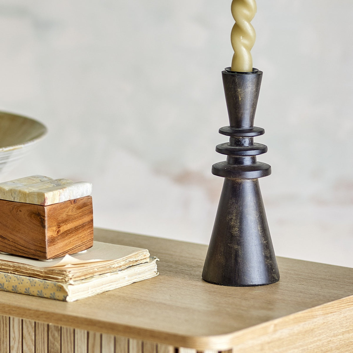 Armel Wooden Candle Holder 20cm in black mango wood, with tapered cup and stacked rings tapering to a wide cone base, holding a twisted candle on a wooden sideboard.