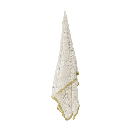 Rovigo Cotton Throw in natural crochet lace weave with scattered coloured stitches and a scalloped yellow edge, hanging against a plain white background.
