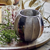 Felecia Striped Glass Christmas Tealight Holder in gold, round recycled glass with vertical ribbed panels and oxidised sheen, shown on a wooden tray with foliage.