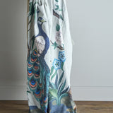 Peacock Throw in green polyester-cotton blend, draped to show a printed peacock, flowering branches and foliage design, against a plain light background.