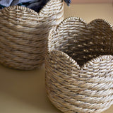 Liam Water Hyacinth Baskets Set of 2 in natural, close-up of two round woven storage baskets with scalloped rims, shown one in front of the other.