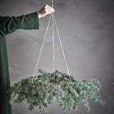 Cedar Artificial Christmas Wreath 70cm in green, held by a cord against a grey background, with frosted cedar sprays and small cones trailing from the ring.
